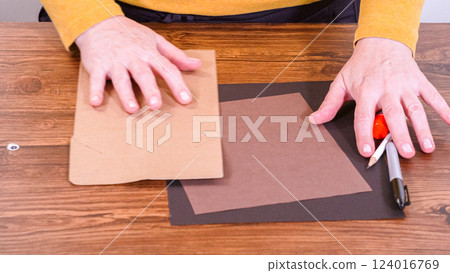 Step by step. Teacher guides online class through making a paper puppet from a brown bag, creatively using a wooden surface as a workspace. 124016769