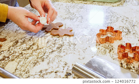 Using various festive cookie cutters, we're cutting out charming gingerbread cookies from the rolled dough on the sleek marble counter, bringing holiday cheer to the modern kitchen. 124016772