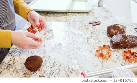 Using various festive cookie cutters, we're cutting out charming gingerbread cookies from the rolled dough on the sleek marble counter, bringing holiday cheer to the modern kitchen. 124016795