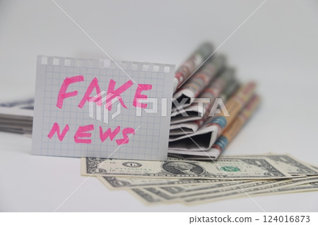 Roll up newspaper with a piece of paper that says fake news, corrupt journalism. Roll up newspaper with a piece of paper that says fake news, corrupt journalism. 124016873