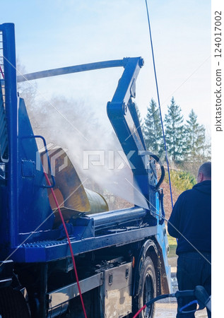 Man washing a blue truck with a high-pressure hose at a self-service car wash. High quality photo 124017002