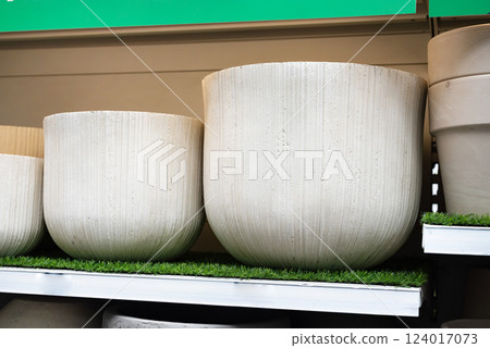 Textured stone planters displayed on shelves in a garden store. Textured stone planters displayed on shelves in a garden store. 124017073