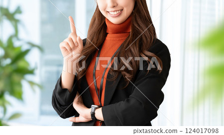 A smiling woman/businesswoman pointing with her index finger up 124017098