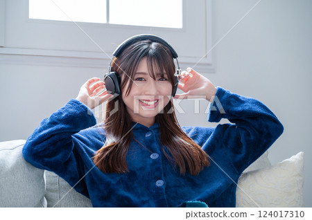 Woman listening to music with headphones in the living room in winter 124017310