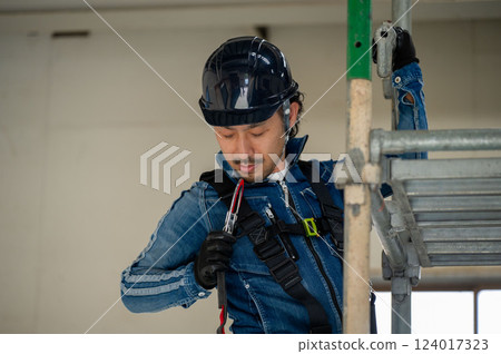 一名戴著安全帽的男子在鷹架上繫上安全帶 124017323