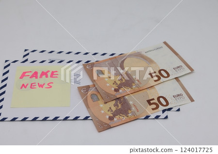 Banknotes in a yellow envelope on a light background. Fake news sticker on the envelope. 124017725