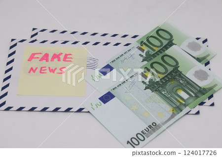 Banknotes in a yellow envelope on a light background. Fake news sticker on the envelope. Banknotes in a yellow envelope on a light background. Fake news sticker on the envelope. 124017726