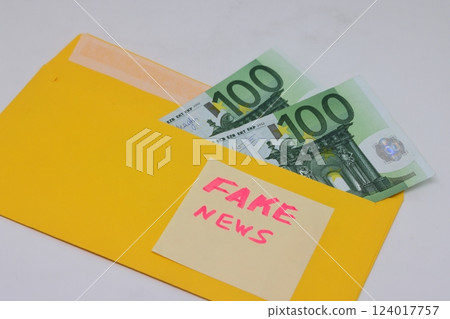 Banknotes in a yellow envelope on a light background. Fake news sticker on the envelope. Banknotes in a yellow envelope on a light background. Fake news sticker on the envelope. 124017757