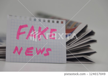 Roll up newspaper with a piece of paper that says fake news, corrupt journalism. 124017849