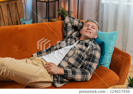 Tired young adult man sitting on comfortable couch, taking a rest daytime nap resting at home room Tired young adult man sitting on comfortable couch, taking a rest daytime nap resting at home room 124017930