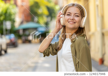 Happy woman in wireless headphones dancing, listening favorite energetic music singing on street Happy woman in wireless headphones dancing, listening favorite energetic music singing on street 124017946