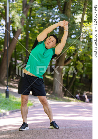 Asian young man sportsman male athletic trainer in good physical shape doing warm-up morning sport Asian young man sportsman male athletic trainer in good physical shape doing warm-up morning sport 124017949