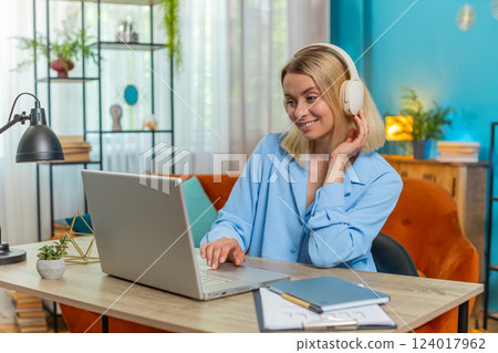 Happy relaxed businesswoman sitting at home office listening to favorite energetic disco music Happy relaxed businesswoman sitting at home office listening to favorite energetic disco music 124017962