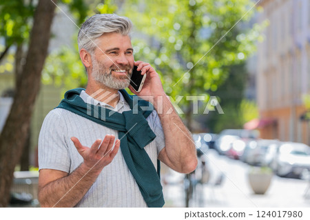 Mature tourist man having remote conversation online talk by smartphone unexpected good news gossip 124017980