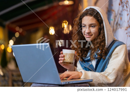 Teenage girl study education online distant job with laptop in city street cafe drinking coffee Teenage girl study education online distant job with laptop in city street cafe drinking coffee 124017991