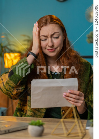Businesswoman girl opening envelope reading bad news in letter feels upset bankruptcy at home office Businesswoman girl opening envelope reading bad news in letter feels upset bankruptcy at home office 124018006