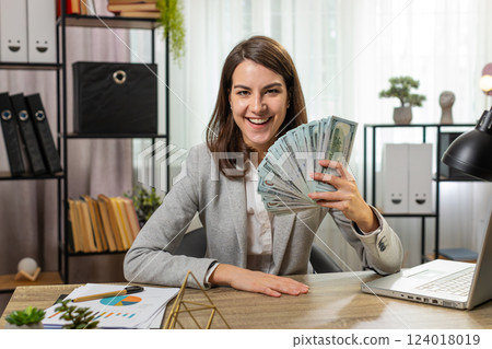 Smiling businesswoman counting cash money dollar checking salary enjoy richness at home office table Smiling businesswoman counting cash money dollar checking salary enjoy richness at home office table 124018019