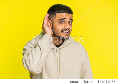 Indian man trying hear you looking confused and frowning, keeping arm near ear for louder voice 124018077