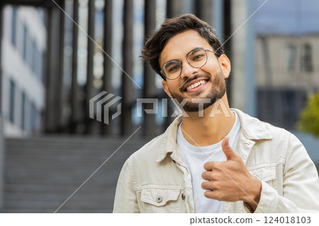 Happy Indian man show thumbs up like sign positive something good positive feedback in city street Happy Indian man show thumbs up like sign positive something good positive feedback in city street 124018103