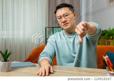 Upset Chinese man showing thumbs down, dislike bad work, disapproval dissatisfied feedback at home Upset Chinese man showing thumbs down, dislike bad work, disapproval dissatisfied feedback at home 124018107