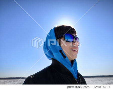 Closeup portrait of young cute caucasian teenager in sunglasses on a winter landscape background. concept of travel, youth, and hope. Dreamy teenage boy on the background of a winter landscape. Closeup portrait of young cute caucasian teenager in sunglasses on a winter landscape background. concept of travel, youth, and hope. Dreamy teenage boy on the background of a winter landscape. 124018205