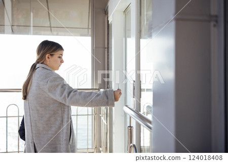 A blonde female teenager applies a card to open the front door of the house. 124018408