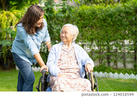 Caregiver help and care Asian senior woman patient sitting on wheelchair at nursing hospital ward, healthy strong medical. Caregiver help and care Asian senior woman patient sitting on wheelchair at nursing hospital ward, healthy strong medical. 124018594