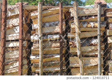 Firewood behind an iron black grate. Place of storage of firewood. Firewood behind an iron black grate. Place of storage of firewood. 124018711