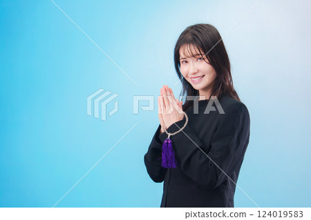 A woman wearing mourning clothes and praying with her hands together (light blue background) 124019583