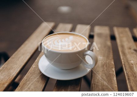 Cup of coffee on the wooden table with latte art. Street coffee, top view. Coffee in a white cup with latte art. Cup of coffee on the wooden table with latte art. Street coffee, top view. Coffee in a white cup with latte art. 124019607