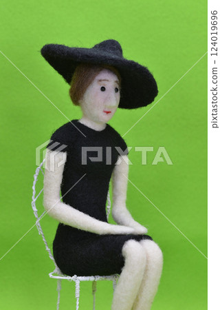 一個戴著帽子坐在椅子上的女娃娃 一個戴著帽子坐在椅子上的女娃娃 124019696