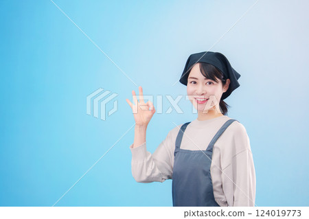 A young woman chef wearing an apron (light blue background) 124019773