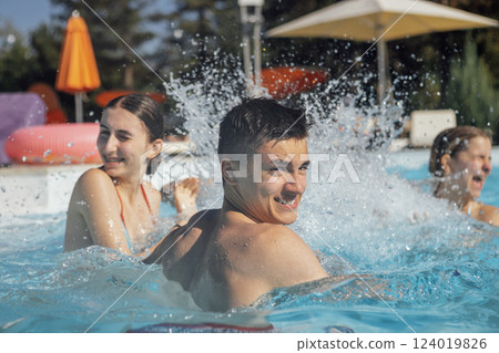 A close-up portrait of a laughing guy in a swimming pool. Joyful teenagers splash and swim in the clear water. A close-up portrait of a laughing guy in a swimming pool. Joyful teenagers splash and swim in the clear water. 124019826