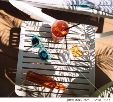 Sunscreens, sunglasses and a delicious chilled cocktail on the pool table 124019833