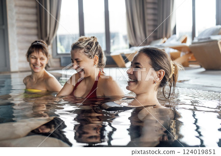 Three young attractive women are laughing and having a great time in the pool 124019851