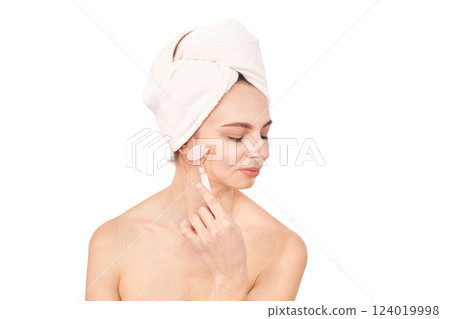 Caucasian female adult with towel wrapped hair using facial roller for skincare Caucasian female adult with towel wrapped hair using facial roller for skincare 124019998