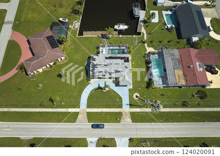 Wind damaged house roof with missing asphalt shingles after hurricane Ian in Florida. Repair of home rooftop concept 124020091
