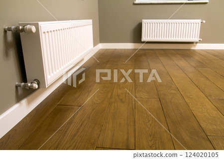 White metal heating radiator mounted on gray wall inside a room. 124020105