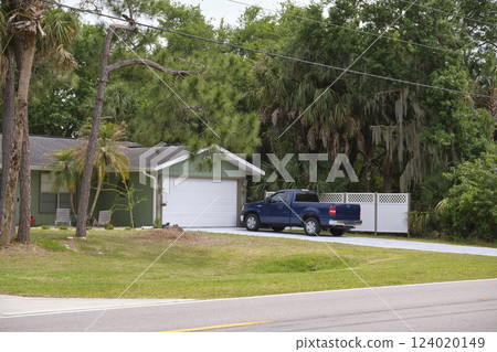 Vehicle parked in front of wide garage double door on paved driveway of typical contemporary american home 124020149