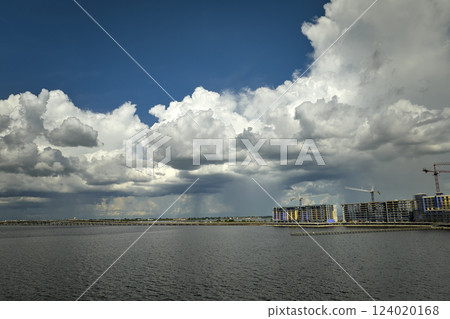 Tower cranes and frame structure of high residential apartment buildings at construction site on sea shore. Real estate development 124020168