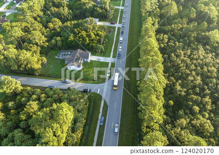 Top view of standard american yellow school bus picking up kids at rural town street stop for their lessongs in early morning. Public transport in the USA 124020170