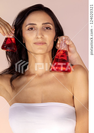 portrait of gorgeous young woman with glass flasks with red liquid portrait of gorgeous young woman with glass flasks with red liquid 124020321