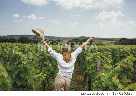 Woman, wearing a hat, in a vineyard in the sun 124020326