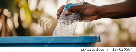 Hand putting Recycling plastic bottle in blue bin, eco-friendly concept, outdoors, 124020504