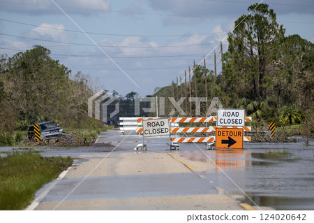 Road closed for roadworks and danger of flooding with warning signs blocking driving of cars Road closed for roadworks and danger of flooding with warning signs blocking driving of cars 124020642