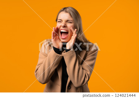Angry businesswoman announce, shouting, holding hand near open mouth. Attention 124021444