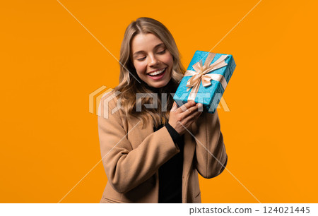 Happy stylish businesswoman gift box, yellow background. Lady smiling,interested 124021445