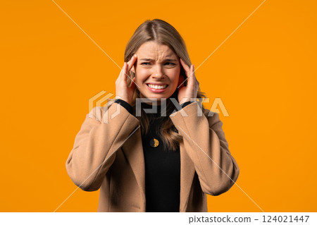 Portrait of businesswoman suffering having headache, yellow studio portrait. Girl putting hands on head. Concept of migraine problems, medicine, illness, magnetic storms concept. 124021447