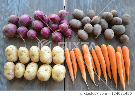 An assortment of whole, organic root vegetables like potatoes, carrots, and beets, laid out on a vintage wooden table in a zero-waste kitchen environment 124021490