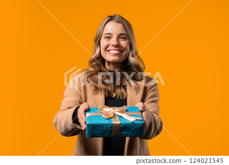 Happy businesswoman gift box on yellow background. Young girl smiling,gives you Happy businesswoman gift box on yellow background. Young girl smiling,gives you 124021545